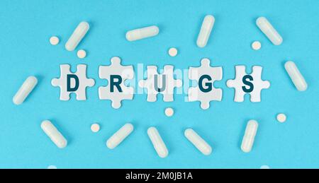 Medizin und Gesundheit. Auf blauem Hintergrund gibt es Pillen und Puzzles mit der Inschrift - DROGEN Stockfoto