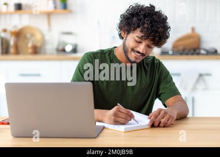 Erfolgreicher Student oder Freiberufler, der am Arbeitsplatz sitzt und mit Laptop-Fernarbeit arbeitet, E-Learning-Konzept Stockfoto