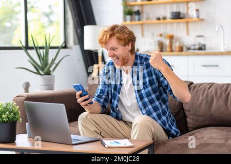 Begeisterter Student oder Freiberufler, der gute Nachrichten in E-Mails liest, erhält eine Zahlung Stockfoto