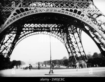 Ein Schwarz-Weiß-Foto aus dem frühen 20.. Jahrhundert, das den Fuß des Eiffelturms in Paris, Frankreich, zeigt. Stockfoto