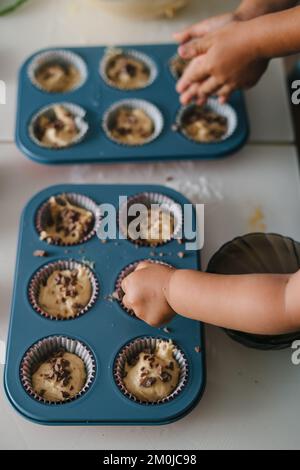 Die Kinderhände streuen Ostern Cupcakes mit Schokolade. Konzept glückliche Familie. Stockfoto