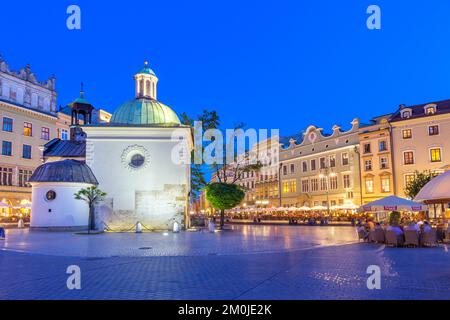 Hauptmarktplatz mit Restaurants und Kirche St. Adalbert in der Innenstadt von Krakau, Polen in der Abenddämmerung. Stockfoto