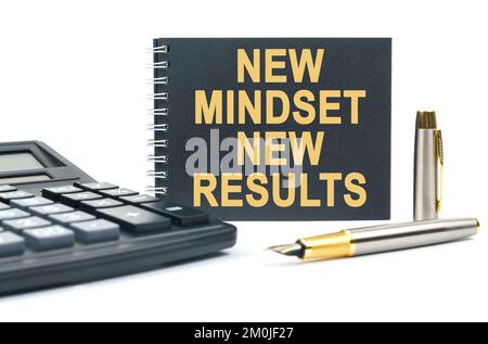 Wirtschaft und Finanzen. Auf weißem Hintergrund befinden sich ein Taschenrechner, ein Stift und ein schwarzes Notizbuch mit der Aufschrift „NEW MINDSET NEW RESULTS“ Stockfoto