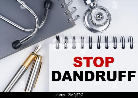Medizin und Gesundheitskonzept. Auf dem Tisch befinden sich ein Stethoskop, ein Stift und ein Notizbuch mit der Aufschrift - STOPP SCHUPPEN Stockfoto