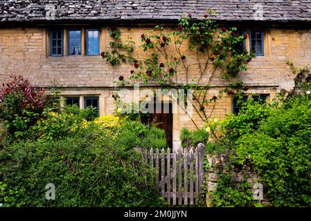 Guiting Power Cottage mit Pfosten und Rosen klettern auf das Steindach. Stockfoto