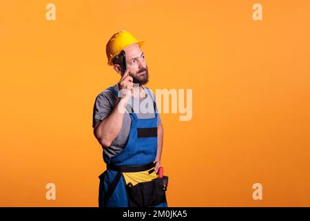 Nachdenklicher Bauarbeiter, der über Renovierungsarbeiten nachdenkt, Ideen sammelt und eine Zange hält. Junge Bauarbeiter, die Werkzeuge benutzen und an Renovierungsarbeiten arbeiten arbeiten. Stockfoto