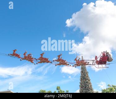 Los Angeles, Kalifornien, USA – 5. Dezember 2022: Der Weihnachtsmann und sein Rentier fliegen in einem Einkaufszentrum in Los Angeles, Kalifornien, durch den blauen Himmel. Stockfoto