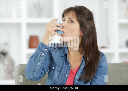 Ein Mädchen, das unter Asthma leidet, indem es seinen Inhalator benutzt Stockfoto