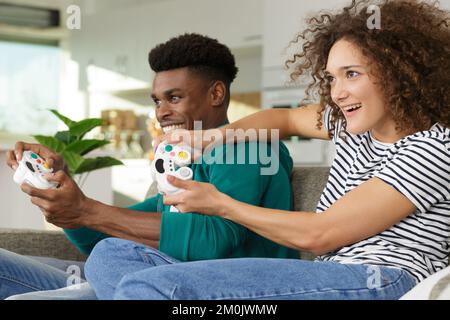 Mann und Frau spielen Videospiele mit Joysticks in den Händen Stockfoto