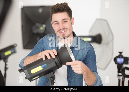 Der Fotograf passt das Blitzlicht im Studio an Stockfoto