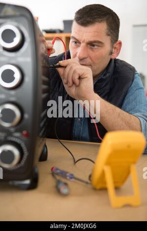 Ein Arbeiter, der Ofen mit einem Multimeter testet Stockfoto