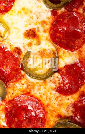 Salami-Peperoni-Pizza-Textur mit Jalapeno als Hintergrund. Eine Pizza aus nächster Nähe. Makrofoto. Peperoni Salami Pizza mit Jalapenos. Stockfoto