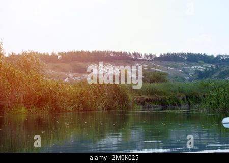 Antike multimillionäre Kreideberge auf der Steppenoberfläche der Erde. Weiße Kreideberge in einer Landschaft mit Fluss und grünen Bäumen Stockfoto