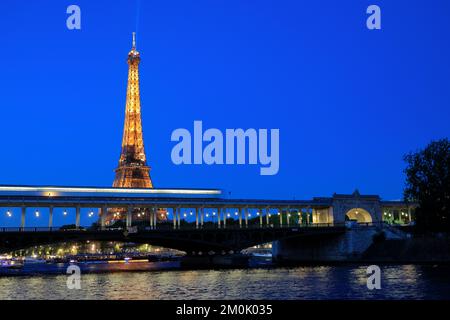 Eiffelturm bei Nacht mit einer U-Bahn, die durch die Brücke Pont de Bir-Hakeim über die seine im Vordergrund fährt. Paris. Frankreich Stockfoto