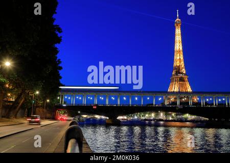 Eiffelturm bei Nacht mit einer U-Bahn, die durch die Brücke Pont de Bir-Hakeim über die seine im Vordergrund fährt. Paris. Frankreich Stockfoto