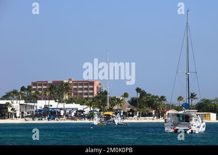 ORANJESTAD, ARUBA - 07. DEZEMBER 2021: Katamaran-Segelboote vor der Reflexions Beach Bar und dem Barefoot Restaurant am Surfside Beach auf Aruba Stockfoto