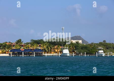 ORANJESTAD, ARUBA - 07. DEZEMBER 2021: Pier am Surfside Beach mit Pinchos Bar and Grill und einigen Motorbooten in Oranjestad auf Aruba Stockfoto