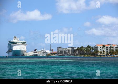 ORANJESTAD, ARUBA - 2. JUNI 2022: Blick auf das Kreuzfahrtschiff, das am Terminal anlegt und auf der rechten Seite das Renaissance Ocean Suites Hotel in Oranjestad auf Aruba Stockfoto