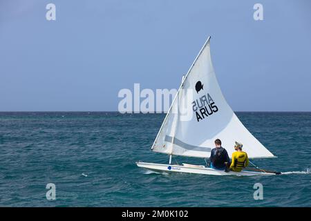 ORANJESTAD, ARUBA - 27. MÄRZ 2022: Zwei Personen segeln in einem kleinen Sonnenfischboot entlang der Küste am Surfside Beach in Oranjestad auf Aruba Stockfoto