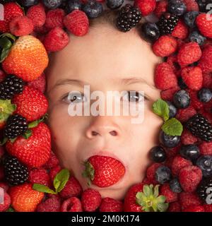 Beerenbanner. Erdbeere, Heidelbeere, Himbeere, Brombeerhintergrund im Gesicht eines Kindes. Gesunde Kinder essen. Die Kinder sehen mit Früchten und Beeren aus. Stockfoto