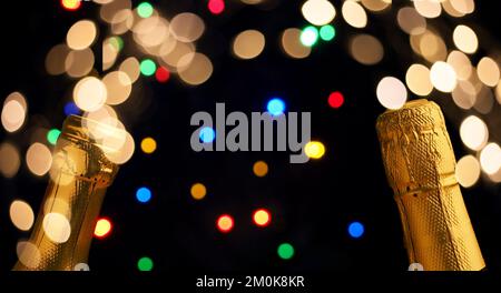 Zwei Flaschen Champagner auf farbenfrohem Bokeh mit Weihnachtsbeleuchtung, Neujahrskonzept Stockfoto