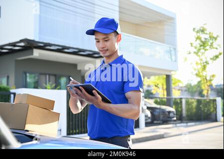 Junger professioneller Zusteller, der das Paket auf dem Tablet überprüft, bevor er es an den Kunden sendet. Versandkonzept, Kurier Stockfoto