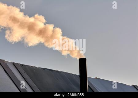 Rauch kommt aus dem Schornstein der Bourgeoisie, der Ofen wird erhitzt. Stockfoto