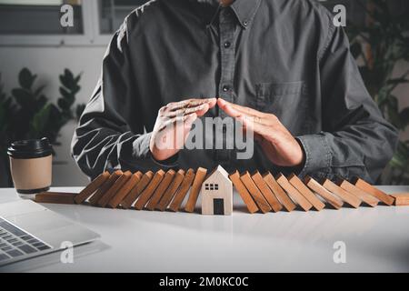 Man Hand blockiert Holzblock aus vielen Reihe fallen Holzblock wie Domino zu Haus Modell Stockfoto