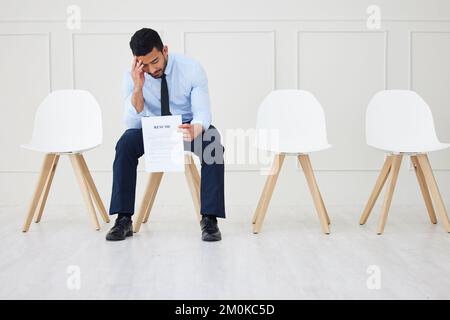Die ganze Länge eines asiatischen Geschäftsmanns, der auf ein Interview wartet. Ein junger gestresster Bewerber, der allein sitzt. Traurige ethnische Berufsausübung, Lebenslauf in Schlange Stockfoto