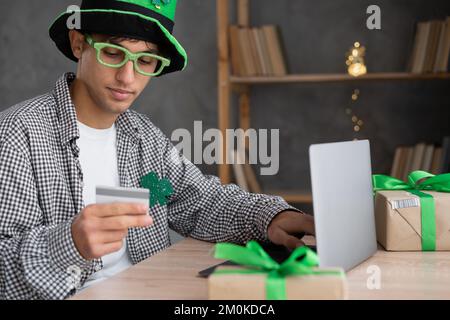 Junger Mann, der Geschenke zum St. Patrick's Day online bestellt. Schließen Stockfoto