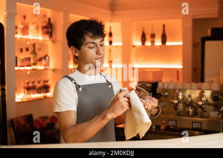 Arabischer Barkeeper, der das Weinglas in der Café-Bar poliert. Speicherplatz kopieren Stockfoto