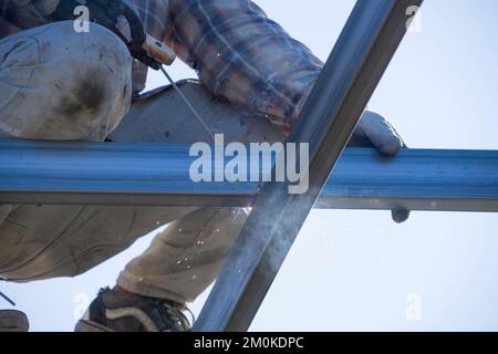Der asiatische männliche Schweißer schweißt Stahlbalken, die gerade renoviert werden. Männlicher Arbeiter im Baugewerbe. Stockfoto