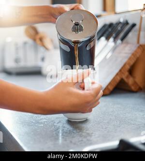 Nahaufnahme von weiblichen Händen, die Kaffee in eine Tasse gießen, die an einer Küchentheke steht. Nicht wiedererkennbare Person, die morgens zu Hause eine Tasse Kaffee trinkt Stockfoto