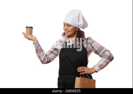 Pretty Woman Barista hält ein Getränk zum Mitnehmen in einem Pappbecher, sieht aus wie ein Traum, wenn es darum geht, Gäste zu bedienen, weißer Hintergrund Stockfoto
