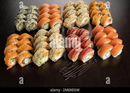 Big Sushi mit frischen Zutaten auf schwarzem Hintergrund. Sushi-Menü. Japanisches Speisekonzept Stockfoto