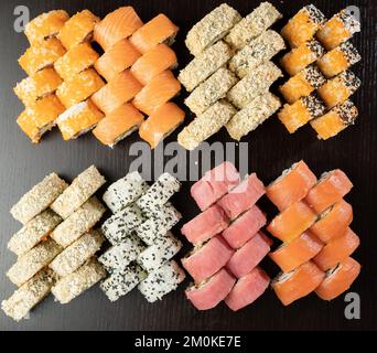 Sushi-Brötchen mit Lachs, Aal, Thunfisch, Avocado, königlicher Garnele, Frischkäse-Philadelphia auf schwarzem Steinbrett. Speicherplatz kopieren Stockfoto