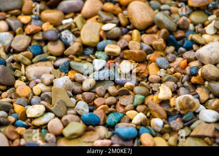 Lebendige Sammlung von bunten Kieselsteinen an einem Sandstrand Stockfoto