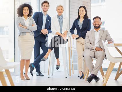 Porträt einer Gruppe selbstbewusster, diverser Geschäftsleute, die in einem Büro zusammenposieren. Glückliche lächelnde Kollegen motiviert und engagiert für den Erfolg Stockfoto