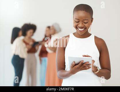 Porträt einer jungen, glücklichen afroamerikanischen Geschäftsfrau, die ein digitales Tablet in einem Büro hält und benutzt. Schwarze Frau lächelt dabei Stockfoto