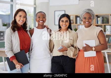 Porträt einer vielfältigen Gruppe von lächelnden ethnischen Geschäftsfrauen, die im Büro zusammenstanden und Technologie und Papierkram in der Hand hatten. Ehrgeizig, glücklich und selbstbewusst Stockfoto