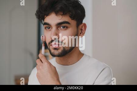 Kaukasier mit Jade-Gesichtswalze zur Hautpflege. Schönheitsbehandlung. Natürliches Massagegerät. Nahaufnahme Hochformat Stockfoto