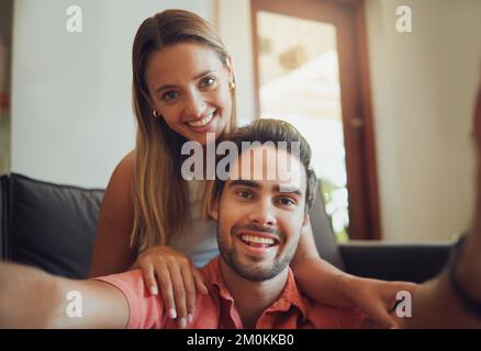 Nahaufnahme des liebenden jungen weißen Paares, das sitzt und Selfie macht, während sie Zeit miteinander verbringen. Ein junger Mann, der ein Handy hält und ein Foto macht Stockfoto