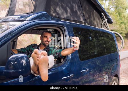 Ein Mann macht ein Selfie, sitzt auf seinem Wohnwagen Stockfoto