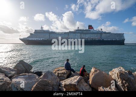 Adelaide, Australien. 7. Dezember 2022 Besucher, die das Luxusschiff RMS Queen Elizabeth sehen, wenn es nach einem kurzen Aufenthalt am Sommerabend vom Passagierterminal Flinders Ports in Adelaide ablegt. Das Schiff Queen Elizabeth, das nach Bali fuhr, wurde nach Fremantle, Westaustralien, umgeleitet, nachdem letzte Woche ein Covid-Ausbruch an Bord aufgetreten war. Kredit: amer Ghazzal/Alamy Live News Stockfoto