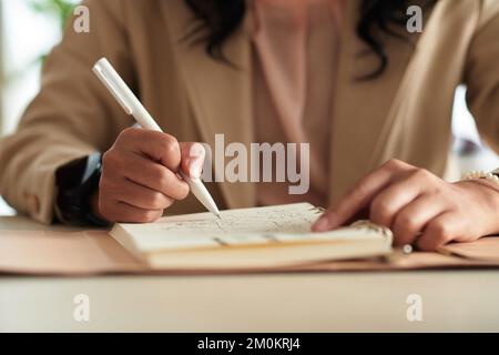 Frau, die im Planer Ideen schreibt und Skizzen zeichnet Stockfoto
