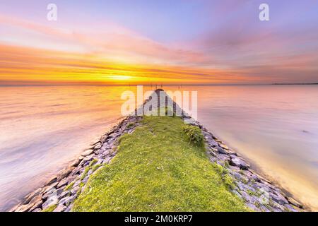 Typischer Bau von Basalt-Wellenbrechern am IJsselmeer in der Nähe der Stadt Hindeloopen in der Provinz Friesland bei Sonnenuntergang, Niederlande. Stockfoto