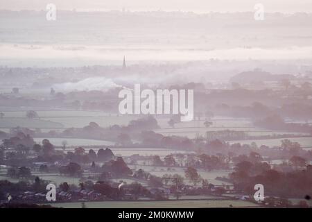 Die Sonne geht über einem nebligen Worcestershire auf, von den Malvern Hills aus gesehen. Das Vereinigte Königreich bereitet sich auf ein Eisklima vor, da Wettervorhersagen sagen sagen, dass die arktische Luft ab Mittwochabend einziehen wird, wobei die britische Gesundheits- und Sicherheitsbehörde einen Kältealarm ausgibt, der den Menschen empfiehlt, ihre Häuser auf mindestens 18C °C zu wärmen (64,4F). Bilddatum: Mittwoch, 7. Dezember 2022. Stockfoto