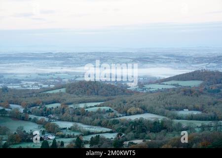 Die Sonne geht über einem nebligen Worcestershire auf, von den Malvern Hills aus gesehen. Das Vereinigte Königreich bereitet sich auf ein Eisklima vor, da Wettervorhersagen sagen sagen, dass die arktische Luft ab Mittwochabend einziehen wird, wobei die britische Gesundheits- und Sicherheitsbehörde einen Kältealarm ausgibt, der den Menschen empfiehlt, ihre Häuser auf mindestens 18C °C zu wärmen (64,4F). Bilddatum: Mittwoch, 7. Dezember 2022. Stockfoto