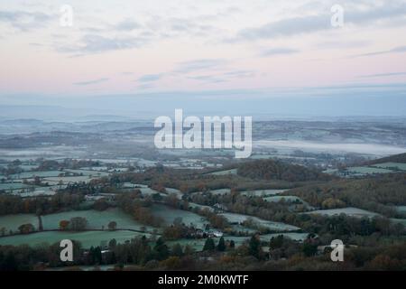 Die Sonne geht über einem nebligen Worcestershire auf, von den Malvern Hills aus gesehen. Das Vereinigte Königreich bereitet sich auf ein Eisklima vor, da Wettervorhersagen sagen sagen, dass die arktische Luft ab Mittwochabend einziehen wird, wobei die britische Gesundheits- und Sicherheitsbehörde einen Kältealarm ausgibt, der den Menschen empfiehlt, ihre Häuser auf mindestens 18C °C zu wärmen (64,4F). Bilddatum: Mittwoch, 7. Dezember 2022. Stockfoto