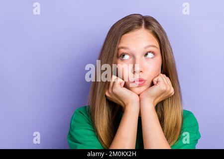 Nahaufnahme Foto Porträt von einer netten, netten, netten Schulkinderin, die interessiert ist, nach leerem Raum auf lila Hintergrund zu suchen Stockfoto